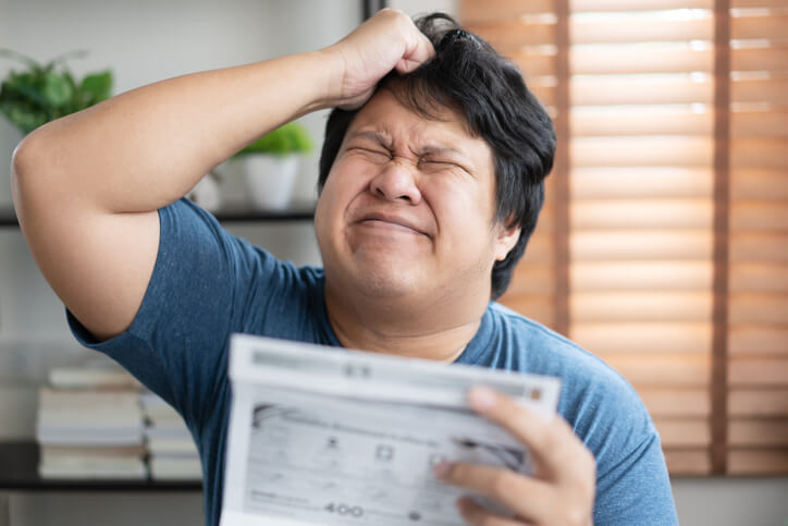 An unhappy driver is stressed looking at the insurance implications of his GA license points on his monthly bill.