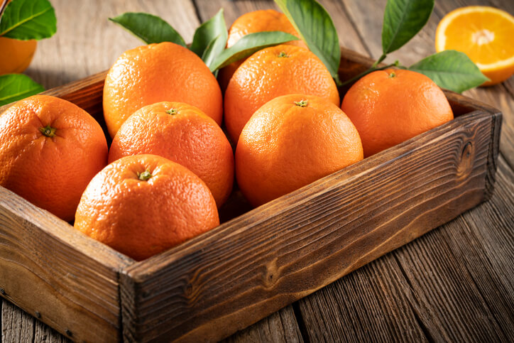 Orange fruits wooden crate box in harvest with orange tree leaves freshly harvested